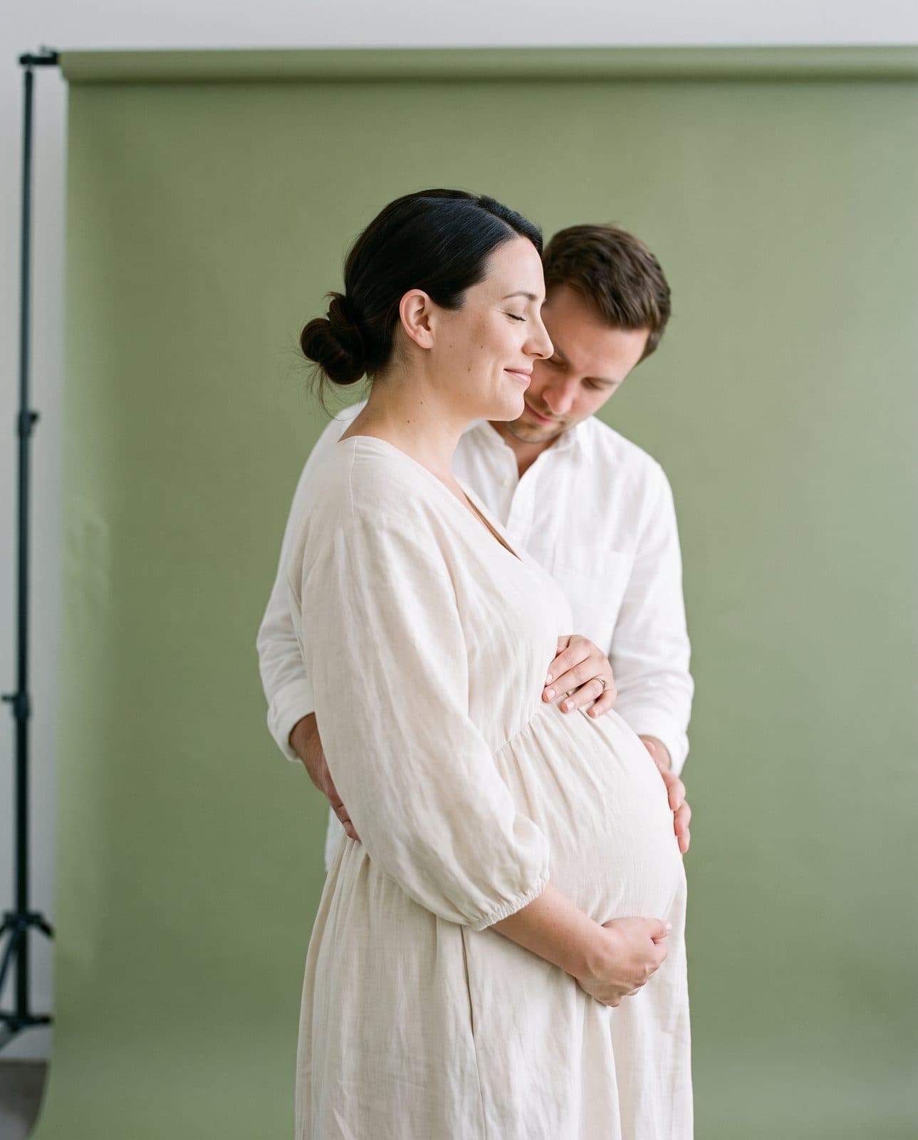Femme enceinte en robe blanche, son compagnon derrière elle