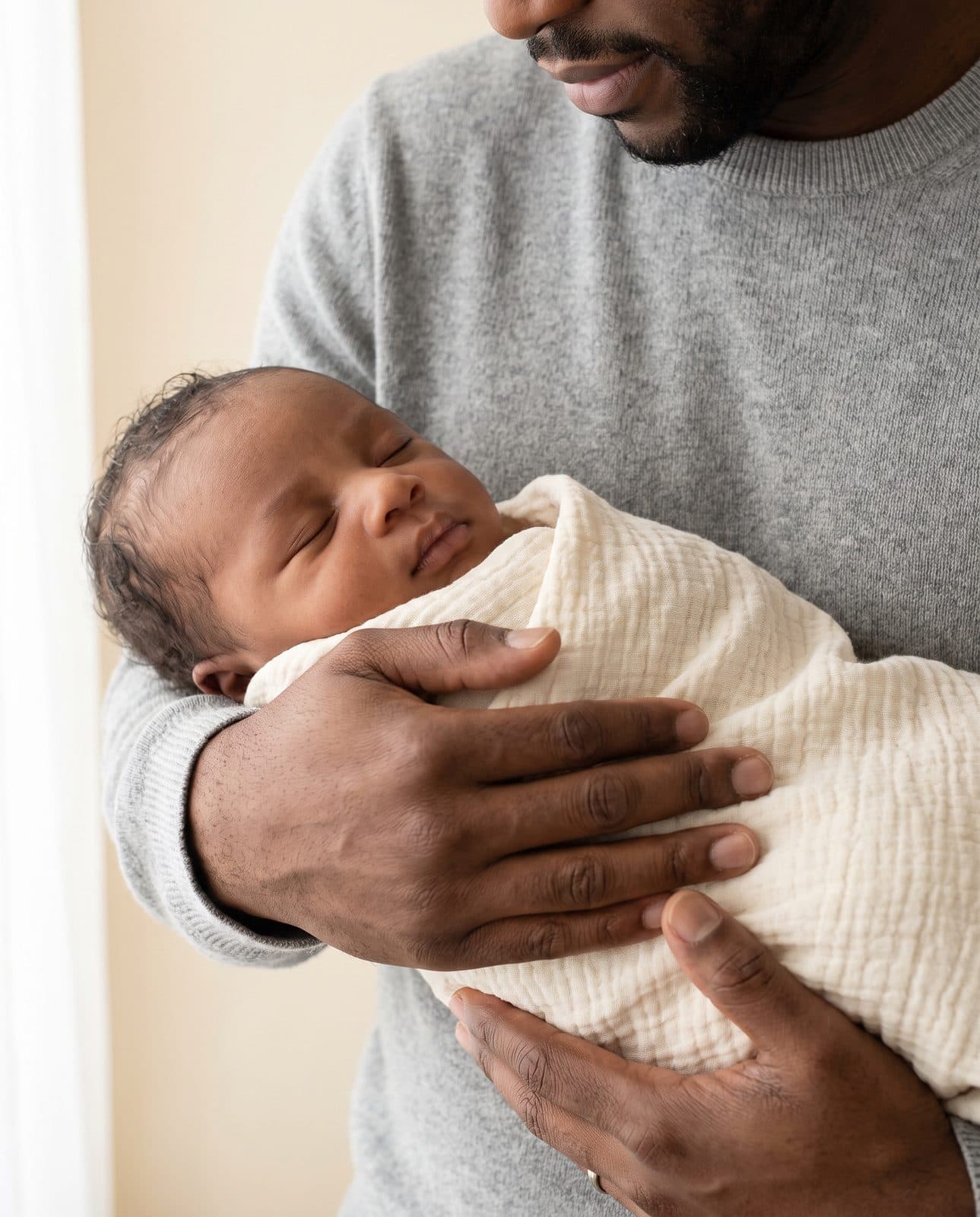 Un nouveau-né endormi dans les mains de son père